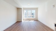 This single-floor residence at 415 Baker Blvd in Tukwila, Washington, offers a clean, contemporary design with a cohesive open layout. Wood-look flooring flows throughout the main living areas, providing a warm and unified aesthetic. The living area is bright and open, benefiting from a large picture window that invites abundant natural light and views of the surrounding neighborhood.

The kitchen is a standout feature, outfitted with white shaker-style cabinetry, granite-look countertops, and a distinctive herringbone-patterned tile backsplash in a soft blue tone. Stainless steel appliances — including a refrigerator, range, and built-in microwave — complete the functional and stylish cooking space. A double-basin stainless steel sink with a modern arc faucet adds further practicality.

An entry corridor connects the main living area to the kitchen, with recessed lighting providing consistent illumination throughout. The bathroom features wood-look flooring, a granite-topped vanity, a glass-enclosed walk-in shower with large-format tile surround, and chrome grab bars, reflecting both style and accessibility-conscious design. Overall, the space presents a modern, light-filled environment with thoughtful finishes throughout.