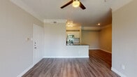 This single-floor residence offers a thoughtfully designed open-concept layout that seamlessly connects the living area to the kitchen. The living room is bright and welcoming, featuring warm hardwood-style flooring, crown molding, a textured ceiling, and a ceiling fan with a built-in light fixture. A sliding glass door with vertical blinds fills the space with natural light and provides access to the outdoors. The kitchen is well-equipped with white shaker-style cabinetry, dark countertops, a light blue subway tile backsplash, and a full suite of stainless steel appliances including a refrigerator, electric range, over-the-range microwave, and dishwasher. A peninsula counter serves as a natural divider between the kitchen and living area, ideal for casual dining or meal prep. The bedroom is generously sized with hardwood-style flooring, a ceiling fan, a window with natural views, and access to a walk-in closet. The bathroom features a soaking tub and shower combination with clean white tile surround. Throughout the residence, neutral warm-toned walls, clean white trim, and consistent flooring create a cohesive and comfortable ambiance.