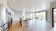 Located at 211 W Mineral St in Milwaukee, WI, this contemporary 3-bedroom, 2-bathroom residence offers a thoughtfully designed open-concept floor plan with modern finishes throughout. Light wood-look flooring flows seamlessly through the entire space, complementing the clean, neutral palette.

The combined kitchen and living area serves as the heart of the home, featuring a large granite-topped island with bar seating, white cabinetry reaching to the ceiling, stainless steel appliances, and pendant lighting. Expansive floor-to-ceiling windows and a sliding glass door to a private balcony flood the space with natural light and offer sweeping views of the Milwaukee skyline and surrounding neighborhood.

The three bedrooms are generously proportioned, each with large corner or oversized windows that frame treetop and city views. The primary bedroom includes direct balcony access and a wall-mounted mini-split system for personalized climate control. Four closets provide ample storage throughout.

Both bathrooms are finished with granite-topped white vanities and wood-look flooring. One features a walk-in shower with tile surround, while the other includes a full soaking tub. A dedicated laundry area and a well-lit hallway connecting the private quarters complete this well-appointed residence.