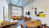 Located in the heart of Richmond, Virginia, this one-bedroom, one-bathroom loft-style residence offers a striking blend of industrial character and modern finishes. Soaring ceilings with exposed concrete beams set a dramatic tone throughout, while polished concrete floors add an urban edge that flows seamlessly across the open-concept layout.

The spacious living area is anchored by oversized industrial-style windows that flood the space with natural light and frame views of the surrounding cityscape. A statement Sputnik chandelier adds a mid-century modern touch overhead, complementing the open, airy atmosphere.

The kitchen is well-appointed with dark cabinetry, granite countertops, a central island with a sink, and a full suite of stainless steel appliances including a refrigerator, range, microwave, and dishwasher. It opens directly to the dining area, making the space ideal for both everyday living and entertaining.

The bedroom offers a tranquil retreat with large windows, high ceilings, and a built-in closet with shelving. The bathroom features tile flooring, a tub-shower combination, a granite-topped vanity with under-cabinet storage, and open wall shelving.

This residence delivers a distinctive loft aesthetic with functional, contemporary design in a prime downtown Richmond location.