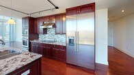 Located in the heart of Uptown Charlotte, this two-story space offers a striking combination of modern architecture and refined interior finishes. The main living area immediately impresses with soaring double-height floor-to-ceiling glass walls that flood the space with natural light and frame panoramic views of the Charlotte skyline. Rich hardwood flooring runs throughout, complementing the clean, white walls and contemporary design. A staircase connects the two levels, with the upper floor featuring an open railed overlook that enhances the sense of vertical space.

The kitchen is well-appointed with deep-toned cabinetry, granite countertops, a mosaic tile backsplash, stainless steel appliances including a large built-in refrigerator, and a central island. The open layout connects seamlessly to the living areas, all bathed in natural light from expansive windows overlooking the city.

The primary bathroom features a double-sink vanity with vessel basins and dark wood cabinetry, marble-tiled floors, a glass-enclosed walk-in shower, and a soaking tub. Additional storage is provided by built-in closets with wire shelving. A half bath with tile flooring and chrome fixtures serves as a functional secondary space. Ceiling fans and access to an outdoor balcony further enhance the livability of this elevated urban residence.