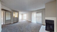 This single-floor residence offers a thoughtfully designed layout that balances comfort and functionality. The expansive living room serves as the centerpiece of the space, featuring plush wall-to-wall carpeting, neutral-toned walls, and a textured ceiling. A tile-framed fireplace anchors one end of the room, while large sliding glass doors fitted with vertical blinds flood the area with natural light and provide access to the outdoors. A secondary window further brightens the space, creating an open and airy atmosphere. Adjacent to the living area, the galley-style kitchen is outfitted with white cabinetry, light countertops, a stainless steel sink, and stainless steel appliances including a refrigerator, range, and overhead microwave. Light wood-style flooring adds a clean, modern touch to the kitchen. A pass-through opening connects the kitchen to the living area, enhancing the sense of openness. The bathroom features an extended vanity with white cabinetry, a large mirror, and light wood-style flooring, complemented by a walk-in closet. The bedrooms are carpeted and filled with natural light; one includes a ceiling fan and sliding glass door opening to a private balcony with outdoor views. Throughout, the space maintains a consistent, neutral palette that is both versatile and inviting.