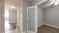 Located at 15 Maple Ave in Barrie, Ontario, this well-appointed 3-bedroom, 2-bathroom unit offers a thoughtfully designed single-floor layout. The open-concept kitchen and living area serves as the heart of the home, featuring rich dark cabinetry extending to the ceiling, stainless steel appliances, a mosaic tile backsplash, and a large central island with a quartz countertop and undermount sink — illuminated by stylish pendant lighting. Light hardwood flooring flows throughout the main living areas, adding warmth and continuity. The three bedrooms are generously proportioned, with the primary bedroom offering ample space for a full suite of furniture. Bedrooms are finished with plush carpeting and large windows that frame scenic outdoor views. The primary ensuite bathroom is a standout, featuring a glass-enclosed walk-in shower, elegant marble-style tile flooring, and a dark wood vanity with quartz countertop. The second bathroom is finished with a full soaker tub and shower combo and clean, neutral tile throughout. A dedicated laundry room accommodates a stacked washer and dryer unit. Two closets and a hallway complete the practical layout. Neutral grey tones throughout create a calm, modern ambiance.