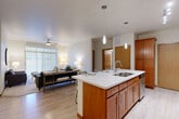 Located at 1609 E 77th St in Sioux Falls, SD, this well-appointed 3-bedroom, 2-bathroom single-floor residence offers a thoughtfully designed open-concept layout. The kitchen is a standout feature, showcasing rich warm-toned cabinetry, marble-look quartz countertops, stainless steel appliances including a range, microwave, and refrigerator, and a large central island with seating for three — ideal for casual dining and entertaining. Pendant lighting and track lighting add a modern touch overhead. The kitchen flows seamlessly into the living room, which is brightened by large windows with vertical blinds, a ceiling fan, and soft carpeting underfoot. The bedrooms are carpeted and generously sized, with the primary bedroom offering ample natural light through wide windows with blinds. Two closets provide well-organized storage with built-in wire shelving systems. Both bathrooms are cleanly finished, featuring warm wood vanities and tub-shower combinations with stylish tile accents. A dedicated in-unit laundry room with a full-size washer and dryer adds everyday convenience. Light wood-style flooring runs through the main living areas, tying the home's warm, neutral palette together throughout.
