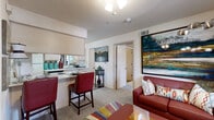 This one-bedroom, one-bathroom unit in Oklahoma City, OK offers a thoughtfully arranged floor plan that maximizes its compact footprint. The open-concept living and kitchen area serves as the heart of the home, where the two spaces flow seamlessly into one another. The kitchen is equipped with light wood cabinetry, a full suite of appliances including a refrigerator, electric range, and dishwasher, along with ample counter space and hard-surface flooring. A pass-through window connects the kitchen to the dining area, where bar-height seating provides a casual dining option. The living room features carpet flooring, a ceiling fan with light fixture, and a window that brings in natural light from outside. The private bedroom is a comfortable retreat with carpet flooring, windows on two walls providing cross-ventilation and natural light, and a ceiling fan overhead. The bathroom includes a tub and shower combination with sliding glass doors, a single vanity with light wood cabinetry, and hard-surface flooring. Throughout the unit, textured ceilings and neutral wall tones create a clean, understated backdrop well-suited to a variety of interior styles.