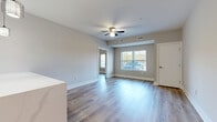 This well-appointed 2-bedroom, 2-bathroom residence in Columbus, Ohio offers a thoughtfully designed single-floor layout with modern finishes throughout. The open-concept kitchen and living area serves as the heart of the home, featuring stylish two-tone cabinetry with dark lower cabinets and crisp white uppers, a striking marble-look peninsula countertop, pendant lighting, a subway tile backsplash, and stainless steel appliances. Light wood-look flooring flows seamlessly through the main living area, complemented by neutral gray walls and a ceiling fan that enhance the bright, airy feel. Natural light fills the living room through large windows with horizontal blinds, offering views of the surrounding outdoors. Both bedrooms are comfortably sized, each with wood-look flooring, ceiling fans or overhead lighting, and windows that bring in natural light. The primary bedroom includes its own closet access. The two bathrooms are finished in a clean, contemporary style with white vanities, white countertops, brushed nickel hardware, and wood-look flooring. Additional conveniences include a dedicated laundry area, multiple closets for ample storage, and utility spaces that support everyday living.