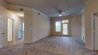 This single-floor residence offers a thoughtfully designed layout that balances comfort and functionality. The spacious living room serves as the heart of the home, featuring plush wall-to-wall carpeting, crown molding, and a ceiling fan with light. A glass-paneled door floods the room with natural light and provides outdoor access, while an adjacent dining and entry area connects seamlessly to the kitchen.

The kitchen is well-equipped with rich dark wood cabinetry, granite-look countertops, a tile backsplash, and stainless steel appliances including a refrigerator, range, and over-the-range microwave. Pendant lighting and light wood-look flooring complete the space, which opens to a breakfast bar for casual dining. An in-unit laundry area is conveniently accessible nearby.

The bedrooms are generously sized with soft carpeting, ceiling fans, and ample natural light from windows with outdoor views. Warm neutral tones create a calm, inviting atmosphere throughout.

The primary bathroom is a standout, offering a double-sink vanity with rich wood cabinetry, a large mirror, a separate walk-in shower with glass doors and tile surround, and a soaking tub set beside a frosted privacy window. Wood-look flooring ties the bathrooms together with a clean, cohesive finish.