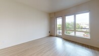Located at 705 N 1st St in Tacoma, Washington, this single-floor unit offers a clean, contemporary design with a neutral color palette and light-toned hardwood-style flooring that runs throughout the space. The layout is efficiently organized, connecting the entry corridor to the main living areas with a smooth, open flow.

The kitchen is a standout feature, equipped with a full suite of stainless steel appliances including a refrigerator, range, microwave, and dishwasher. Rich, dark espresso-toned cabinetry extends to the ceiling, providing generous storage, while light countertops offer a crisp contrast. Recessed lighting illuminates the kitchen and hallway areas effectively.

The main living area is bright and open, benefiting from large windows and sliding glass door access to a private balcony. Outdoor views of surrounding greenery and the Tacoma cityscape enhance the sense of openness. A secondary room provides a versatile, clean space with warm flooring and ample wall space.

The hallway features a sliding barn-style door and a built-in closet with wire shelving, offering practical storage solutions. The bathroom is finished with dark cabinetry, a white countertop vanity with an undermount sink, a large mirror, and light flooring, maintaining the consistent modern aesthetic found throughout the unit.