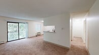 Located at 101 Longmeadow Drive in Holbrook, MA, this single-floor, three-bedroom, one-bathroom home offers a thoughtfully laid-out interior with comfortable, carpeted living spaces throughout. The open-concept living and dining area serves as the heart of the home, featuring large sliding glass doors that flood the space with natural light and provide access to an outdoor balcony with views of surrounding greenery. A wall-unit heater and baseboard heating ensure year-round comfort. The galley-style kitchen is well-appointed with warm wood cabinetry, granite countertops, black appliances including a range and refrigerator, a stainless steel sink, and tile flooring — connecting conveniently to the bathroom beyond. The bathroom features tile flooring, a wood vanity with granite countertop, and clean, neutral finishes. Each of the three bedrooms is carpeted and naturally lit by windows overlooking the wooded surroundings, with baseboard heating. The primary bedroom offers a spacious built-in closet with louvered doors, while additional closets throughout the home provide ample storage, including a walk-in closet with wire shelving. A dedicated entrance and hallway complete the functional floor plan of this well-organized home.