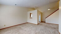 Located at 1525 SR-303 in Streetsboro, Ohio, this two-floor residence offers a well-organized layout with notable architectural details throughout. The main living area features soaring vaulted ceilings accented by a ceiling fan and track lighting, creating an open and airy atmosphere. Plush wall-to-wall carpeting runs throughout the living spaces, complemented by warm wood baseboards that add a classic finishing touch.

The kitchen is efficiently designed in an L-shaped configuration, featuring white cabinetry with wood-trimmed accents, white countertops, a double-basin sink, a dishwasher, and a stove. A window above the sink allows natural light to brighten the workspace. A distinctive pass-through opening connects the kitchen visually to the main living area, enhancing the sense of openness between the two spaces.

The upper level includes carpeted bedrooms, one of which features prominent vaulted ceilings that add volume and character. Natural light filters in through windows, lending each room a bright and welcoming quality. The bathrooms are consistently appointed with tile flooring, single-sink vanities with wood-framed cabinetry, and tub-shower combinations with marble-patterned surrounds. A staircase with a wood railing connects the two floors, contributing to the home's cohesive and functional design.