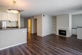 Located at 3655 S Bear St in Santa Ana, California, this single-floor unit offers a well-organized, open layout designed for functional everyday living. The main living area is generously sized, finished with rich wood-tone laminate flooring that extends throughout the space. A classic fireplace anchors one wall, flanked by built-in shelving that provides both display and storage opportunities. Neutral, light-toned walls keep the space feeling bright and versatile.

The living area flows openly toward the dining space, which benefits from a sliding glass door that introduces natural light and connects the interior to the outdoors. A pendant light fixture overhead defines the dining zone within the open plan.

The kitchen features dark granite countertops contrasted against white cabinetry, offering ample storage and counter workspace. Stainless steel appliances, including a refrigerator and gas range, are included, along with a dishwasher and a stainless sink. A raised counter peninsula provides a natural boundary between the kitchen and living areas.

The bathroom includes a vanity with white cabinetry, a large mirror with overhead lighting, and a clean, bright finish. Notably, a stacked washer and dryer unit is conveniently located adjacent to the bathroom, adding practical in-unit laundry access. Textured ceilings are present throughout the space.