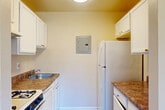 This single-floor, 2-bedroom, 1-bathroom unit at 5521 Marlboro Pike in District Heights, MD offers a practical and functional layout. The living room is a notable highlight, featuring large sliding glass doors that open to a private balcony overlooking a landscaped green area with mature trees, filling the space with natural light and providing pleasant outdoor views. The carpeted flooring throughout the living and bedroom areas adds warmth and comfort to the overall ambiance.

The galley-style kitchen is efficiently designed with white cabinetry, brown laminate countertops, a gas range, a full-size refrigerator, and wood-look flooring, maximizing every inch of available space. Both bedrooms are carpeted and finished with neutral-toned walls. The primary bedroom is a comfortable size and includes access to a dedicated closet with built-in shelving and hanging rods. The second bedroom features a wide window that brings in natural light and views of the surrounding area.

The single bathroom is clean and straightforward, equipped with a full tub-shower combination featuring white tile surround and chrome fixtures. Overall, the unit presents a simple, no-frills layout well-suited for efficient everyday living.