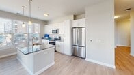 Located at 1906 Research Center Dr in Blacksburg, Virginia, this well-appointed single-floor unit offers a clean, contemporary design throughout. The kitchen serves as a central highlight, featuring crisp white shaker cabinetry, granite countertops, a large center island with an undermount sink, stainless steel appliances including a French door refrigerator, electric range, and built-in microwave, all illuminated by stylish pendant lighting. Light wood-style flooring flows through the kitchen and living areas, enhancing the bright, airy feel complemented by large windows that bring in natural light and exterior views. The living and dining areas are open and functional, with ceiling fans providing comfort. Bedrooms are finished with plush carpet and receive natural light through windows. At least one bedroom includes a spacious walk-in closet outfitted with wire shelving systems offering generous storage capacity. The bathrooms feature granite-topped vanities with white cabinetry, framed mirrors, and tub-shower combinations with brushed nickel fixtures. Wood-look flooring in the bathrooms ties the finishes together cohesively. The unit's neutral color palette and modern finishes create a fresh, move-in-ready environment throughout.