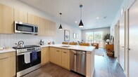 Located at 394 West Ave in Norwalk, CT, this well-appointed one-bedroom, one-bathroom residence offers a thoughtfully designed single-floor layout with modern finishes throughout. The open-concept living area features dark hardwood-style flooring, recessed lighting, and a sliding glass door that opens to a private balcony overlooking the community courtyard and pool area, flooding the space with natural light and outdoor views.

The kitchen is a standout feature, showcasing light wood flat-front cabinetry, stainless steel appliances including a full-size refrigerator, gas range, and built-in microwave, as well as a white quartz peninsula with bar seating and stylish pendant lighting — ideal for both everyday cooking and casual dining.

The bedroom is a comfortable retreat with plush carpeting, large windows that draw in natural light, and ample space for furnishings. The bathroom is clean and contemporary, featuring a wood-tone vanity with a white countertop, large-format tile flooring, and a walk-in glass-enclosed shower.

The living room provides a welcoming gathering space anchored by warm textures and natural light, completing this efficiently designed and modern residence in the heart of Norwalk.