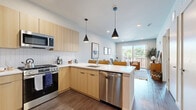 Located at 394 West Ave in Norwalk, CT, this well-appointed one-bedroom, one-bathroom residence offers a thoughtfully designed single-floor layout with modern finishes throughout. The open-concept living area features dark hardwood-style flooring, recessed lighting, and a sliding glass door that opens to a private balcony overlooking the community courtyard and pool area, flooding the space with natural light and outdoor views.

The kitchen is a standout feature, showcasing light wood flat-front cabinetry, stainless steel appliances including a full-size refrigerator, gas range, and built-in microwave, as well as a white quartz peninsula with bar seating and stylish pendant lighting — ideal for both everyday cooking and casual dining.

The bedroom is a comfortable retreat with plush carpeting, large windows that draw in natural light, and ample space for furnishings. The bathroom is clean and contemporary, featuring a wood-tone vanity with a white countertop, large-format tile flooring, and a walk-in glass-enclosed shower.

The living room provides a welcoming gathering space anchored by warm textures and natural light, completing this efficiently designed and modern residence in the heart of Norwalk.