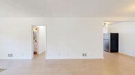 Located on N Hayworth Ave in West Hollywood, CA, this 2-bedroom, 1-bathroom unit offers a clean, modern aesthetic across a single floor. Light wood-toned flooring runs consistently throughout all rooms, creating a cohesive and airy feel. The open living area is bright and welcoming, with recessed and pendant lighting adding warmth to the neutral white walls.

The kitchen is well-appointed with white shaker cabinets, light stone countertops, a stainless steel dishwasher, a gas range with a sleek wall-mounted hood, and a full-size refrigerator. A window above the sink allows natural light to filter in, and a modern globe chandelier adds a stylish accent.

The primary bedroom is generously sized, featuring three windows that frame views of surrounding greenery and flood the room with natural light. Black curtain rods with sheer white panels add a contemporary touch. The second bedroom also benefits from natural light through dual windows and includes a built-in double closet with matte black hardware.

The bathroom is finished in crisp white tones with a tub-shower combination, a white vanity, and matte black fixtures throughout. A hallway connects the rooms, contributing to an efficient and practical layout. The overall ambiance is light, clean, and move-in ready.