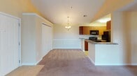 This single-story residence at 9001 SR-21 S in Port Wentworth, Georgia, offers a well-organized layout with a warm, neutral color palette of soft golden-yellow walls and white trim throughout. The living area features vaulted ceilings with a ceiling fan and is brightened by a sliding glass door that opens to an outdoor space, allowing ample natural light to fill the room. Plush carpeting extends across the living and bedroom areas, while tile flooring is found at the entryway and in the kitchen and bathrooms.

The kitchen is efficiently designed with a galley-style configuration, featuring warm-toned wood cabinetry, granite-look countertops, black appliances including a refrigerator, electric range, and dishwasher, and a peninsula that opens toward the dining and living area. A pendant chandelier marks the dining space adjacent to the kitchen, which also includes a double-door closet for additional storage.

Two bedrooms offer carpeted floors, natural light from windows with blinds, and ample wall space. Both bathrooms are finished with tile flooring and include a tub-shower combination. The primary bathroom features built-in shelving within the shower surround and dark granite-look countertops at the vanity.