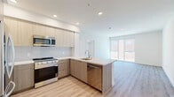 Located at 988 S Manhattan Place in Los Angeles, this modern 2-bedroom, 2-bathroom single-floor unit offers a well-designed, contemporary living experience. Light wood-tone flooring flows consistently throughout, creating a clean and cohesive aesthetic across every room.

The open-concept kitchen is a standout feature, outfitted with flat-front cabinetry in a warm wood finish, a white tile backsplash, quartz countertops, and a full suite of stainless steel appliances including a gas range, over-range microwave, dishwasher, and refrigerator. A peninsula with an undermount sink extends the counter space and connects the kitchen to the living area, which benefits from large windows that bring in generous natural light and views of the surrounding neighborhood.

Both bedrooms are bright and well-proportioned, with the primary bedroom featuring expansive sliding glass doors that frame outdoor views and allow abundant sunlight. The second bedroom also includes a large window. Two dedicated closets provide organized storage, one of which includes built-in shelving and dual hanging rods.

The bathrooms are finished with modern tile work, including a full tub-shower with gray subway tile surround, light wood vanity cabinetry, and tile flooring. An in-unit laundry area with a stacked washer and dryer adds everyday convenience to this thoughtfully appointed home.