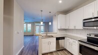 Located at 1295 Dresden Dr NE in the desirable Brookhaven neighborhood of Atlanta, GA, this single-floor residence offers a thoughtfully designed open-concept layout with contemporary finishes throughout. The kitchen is a standout feature, showcasing crisp white shaker cabinetry, granite countertops, and a classic white subway tile backsplash. A full suite of stainless steel appliances — including a refrigerator, electric range, over-the-range microwave, and dishwasher — is complemented by stylish pendant lighting that adds a modern touch. The kitchen flows seamlessly into the living area, which is bathed in natural light from large windows and a set of French doors that open to the outside. Wood-style plank flooring runs throughout the main living spaces, lending warmth and cohesion to the open floor plan. A ceiling fan adds both function and comfort to the living area. The bedroom is generously proportioned, featuring the same wood-style flooring, a ceiling fan, and access to a walk-in closet. The bathroom is cleanly appointed with a white vanity, quartz countertop, undermount sink, brushed nickel fixtures, a full tub-shower combination with white tile surround, and neutral tile flooring. The overall ambiance is clean, bright, and move-in ready.