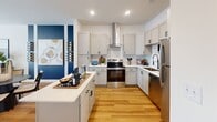 Located at 10500 Royal Grove Rd in China Grove, NC, this 2-bedroom, 2-bathroom residence offers a thoughtfully designed single-floor layout with modern finishes and a cohesive, contemporary aesthetic throughout. The open-concept kitchen, dining, and living area serves as the heart of the home, featuring grey shaker-style cabinetry, stainless steel appliances, a sleek center island with white quartz countertops, and a wall-mounted range hood — all set atop warm hardwood-style flooring. A bold navy accent wall adds a striking visual element that ties the living and dining areas together seamlessly. The living room benefits from French doors that invite abundant natural light and provide outdoor access. Both bedrooms are carpeted for comfort and include ceiling fans, generous windows, and dedicated closets with built-in shelving and hanging rods. The primary bedroom is spaciously sized with ample room for a full furniture arrangement. The two bathrooms mirror the kitchen's design language, featuring grey vanities with white countertops and clean, bright finishes. A hallway connects the private quarters to the main living space, maintaining a clear and functional flow throughout the home.