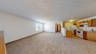 Located at 268 Summerfern Ln in Columbus, OH, this one-bedroom, one-bathroom unit offers a well-organized, single-floor layout that makes efficient use of its space. The open-concept living and kitchen area serves as the heart of the home, where the two spaces flow naturally into one another. The kitchen is equipped with warm honey-toned wood cabinetry, a white electric range, a refrigerator, and a peninsula counter that separates it from the living area, providing both functional workspace and a visual anchor for the room. A window in the living room brings in natural light, creating a bright and welcoming atmosphere. Textured ceilings are present throughout, adding a classic residential character. The bedroom is a comfortable, well-proportioned space featuring plush wall-to-wall carpeting, a window with blinds for natural light and privacy, and easy access to the hallway. The bathroom is clean and functional, featuring a full tub-and-shower combination with chrome fixtures and tile-style flooring. Hallways connecting the rooms provide a logical flow throughout the unit. Neutral wall tones and consistent carpeting throughout the main living areas and bedroom contribute to a cohesive and move-in ready aesthetic.