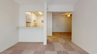 Located at 2414 Nutwood Ave in Fullerton, California, this single-story unit offers a straightforward, functional layout designed for comfortable everyday living. The interior is finished with neutral tones throughout, creating a clean and cohesive atmosphere across all rooms.

The living area is generously sized, featuring wall-to-wall carpet and a ceiling fan overhead. Large windows dressed with vertical blinds allow ample natural light to filter in, brightening the space throughout the day. A wall-mounted air conditioning unit provides climate control. The open layout connects seamlessly to the kitchen via a pass-through counter, enhancing the sense of openness between the two spaces.

The kitchen is equipped with white cabinetry offering substantial storage above and below the counters, complemented by speckled laminate countertops. A double stainless steel sink, a gas range, and a built-in microwave complete the functional setup, with tile flooring underfoot.

The bathroom features tile flooring, a vanity with matching speckled countertops, mirrored medicine cabinets, and a separate tub/shower room. A walk-in closet is conveniently accessible from the bathroom area. A hallway with a tall wall-mounted heater unit connects the main living spaces, adding to the unit's practical design.