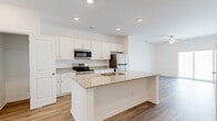Located at 2108 Silty Soil Ct in Leland, NC, this thoughtfully designed two-story home offers a clean, contemporary aesthetic across two well-proportioned floors. The main level features an open-concept layout where the kitchen flows seamlessly into the living area. The kitchen is outfitted with crisp white shaker cabinetry, granite countertops, a center island with an undermount sink, and a full suite of stainless steel appliances, including a refrigerator, range, and built-in microwave. Light hardwood-style flooring runs throughout the main level, complemented by recessed lighting and a ceiling fan in the living area. A staircase connects the two floors, with hallways providing easy access to all rooms. The upper level houses two bedrooms, including a generously sized primary suite with its own walk-in closet and a private bathroom featuring granite countertops and hardwood-style flooring. Additional closets throughout the home provide ample storage. The home also includes an attached garage with an automatic opener. Bright, neutral interiors and multiple windows allow natural light to fill each room, creating a welcoming and functional living environment.