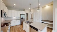 Located at 3612 Beverly Cove Way in Wilmington, NC, this single-floor home offers a clean, modern aesthetic with thoughtfully selected finishes throughout. The open-concept layout creates a seamless flow from the entry into the main living and kitchen areas, all unified by warm light hardwood flooring.

The kitchen is a standout feature, designed for both function and style. White shaker cabinetry extends to the ceiling, paired with a classic subway tile backsplash and quartz countertops in a warm gray tone. A center island with an undermount sink and pendant lighting in an antique brass finish serves as a focal point, while stainless steel appliances — including a French door refrigerator, electric range, built-in microwave, and dishwasher — complete the space. A walk-in pantry provides generous storage.

The bathroom continues the home's consistent design language with white shaker vanity cabinetry, a quartz countertop, framed mirror, and brushed nickel hardware accents. The space is bright, clean, and efficiently laid out.

Additional rooms feature neutral wall tones and natural light through white-trimmed windows, offering versatile spaces suitable for bedrooms or a home office. Recessed lighting and ceiling fans are present throughout, enhancing comfort and functionality in this well-appointed single-level home.
