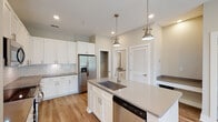 Located at 3612 Beverly Cove Way in Wilmington, NC, this single-floor home offers a clean, modern aesthetic with thoughtfully selected finishes throughout. The open-concept layout creates a seamless flow from the entry into the main living and kitchen areas, all unified by warm light hardwood flooring.

The kitchen is a standout feature, designed for both function and style. White shaker cabinetry extends to the ceiling, paired with a classic subway tile backsplash and quartz countertops in a warm gray tone. A center island with an undermount sink and pendant lighting in an antique brass finish serves as a focal point, while stainless steel appliances — including a French door refrigerator, electric range, built-in microwave, and dishwasher — complete the space. A walk-in pantry provides generous storage.

The bathroom continues the home's consistent design language with white shaker vanity cabinetry, a quartz countertop, framed mirror, and brushed nickel hardware accents. The space is bright, clean, and efficiently laid out.

Additional rooms feature neutral wall tones and natural light through white-trimmed windows, offering versatile spaces suitable for bedrooms or a home office. Recessed lighting and ceiling fans are present throughout, enhancing comfort and functionality in this well-appointed single-level home.