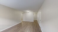 This single-floor, 1-bedroom, 1-bathroom unit in Memphis, Tennessee is designed for comfortable everyday living with a clean, neutral aesthetic throughout. The living room greets you at the entrance with warm wood-look flooring, a large window that invites natural light, and a textured ceiling that adds subtle character. The open flow leads into a combined dining and kitchen area, where white cabinetry, a white appliance suite including a range and refrigerator, and a functional countertop layout make the kitchen both practical and easy to navigate. A hallway connects the main living areas to the private spaces, with utility rooms offering additional functionality. The spacious bedroom features plush wall-to-wall carpeting, a window with natural light, and access to generous closet space, including a walk-in closet with built-in shelving for ample storage. The full bathroom is finished with clean white tile surrounding a tub-shower combination, wood-look flooring, and a vanity with a sink. Additional closets throughout the unit provide exceptional storage for a residence of this size. The overall palette of soft gray and white tones, consistent flooring materials, and practical layout make this a well-organized and move-in ready space.