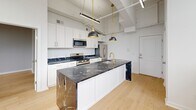Located at 36 N Narberth Ave in Narberth, PA, this thoughtfully designed one-bedroom, one-bathroom unit makes efficient use of its compact footprint across a single floor. The open-concept layout maximizes the sense of space, with light hardwood flooring flowing seamlessly throughout.

The kitchen serves as a striking centerpiece, showcasing white shaker cabinetry with gold hardware paired with a bold black marble waterfall island. Stainless steel appliances, including a range, built-in microwave, and refrigerator, complement the sophisticated design. Elevated ceilings with exposed structural elements and sleek pendant lighting lend an industrial-modern character to the space.

The bedroom is a calm, neutral retreat featuring light walls, hardwood floors, and a black-framed window that brings in natural light and outdoor views. A dedicated closet adds practical storage. The adjacent hallway connects seamlessly to both the bedroom and the bathroom.

The bathroom is a standout feature, finished with floor-to-ceiling Calacatta marble-style tile in the walk-in glass shower, accented by grey hexagonal mosaic floor tiles and chrome fixtures, delivering a polished, spa-like atmosphere.

Overall, the unit combines modern finishes with a clean, minimalist aesthetic, offering an elevated living experience in a compact and functional space.