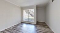 This single-floor residence offers a well-designed layout that balances comfort and functionality across its living spaces. The main living areas are finished with durable wood-look flooring in a cool gray tone that reflects natural light beautifully, creating a bright and airy atmosphere. Crown molding details add a polished architectural touch to the primary living spaces, which feature large windows dressed with vertical blinds that allow generous daylight to pour in while offering views of the surrounding greenery.

The bedrooms are finished with soft, plush carpeting underfoot, providing a warm and comfortable feel. Each bedroom is fitted with windows dressed in horizontal blinds, ensuring both natural light and privacy. Select bedrooms include ceiling fans for added comfort. The rooms offer clean, neutral-toned walls throughout, providing a versatile backdrop adaptable to a variety of interior styles.

The overall floor plan, as seen in the overhead dollhouse view, reveals a thoughtfully arranged layout with a functional flow between the living area, kitchen, bedrooms, and bathrooms. The consistent use of neutral tones — soft whites, warm beiges, and light grays — throughout the space creates a cohesive, calm aesthetic. The abundance of windows across all rooms ensures the entire residence remains well-lit and connected to the outdoors.
