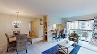This thoughtfully designed one-bedroom, one-bathroom residence makes excellent use of its single-floor layout, offering a comfortable and cohesive living environment. The open-concept main area seamlessly connects the living room, dining room, and kitchen, creating a fluid and functional space ideal for everyday living and entertaining.

The living room features plush carpeting, soft neutral tones, and a large window that invites natural light and outdoor views. A built-in shelving unit with a wall-mounted desk serves as a practical divider between the living and dining areas, adding both character and utility. The dining area is anchored by a warm wood table beneath an elegant chandelier, lending a refined yet relaxed atmosphere.

The galley-style kitchen is efficiently arranged with ample white cabinetry, a double-basin sink, and a window that brightens the workspace. Tile flooring and clean countertops contribute to a tidy, functional design.

The bedroom is a well-proportioned retreat featuring a window with outdoor views, carpeted floors, and direct access to a dedicated closet. The full bathroom is clean and straightforward, complete with a vanity, toilet, and a shower-tub combination. Throughout the residence, a cohesive coastal-inspired aesthetic ties the rooms together with a light, inviting ambiance.