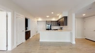 This single-floor residence offers two bedrooms and two bathrooms within a well-organized layout designed for comfortable living. Light-toned tile flooring runs consistently throughout the unit, creating a cohesive and easy-to-maintain foundation across all rooms.

The kitchen serves as a central feature of the home, equipped with dark espresso-toned cabinetry that extends to the upper walls, providing ample storage. Black appliances—including a refrigerator, range, and built-in microwave—complement the cabinetry, while light quartz countertops offer a crisp contrast. A peninsula with an integrated sink extends into the open living area, enabling flexible use of the space. Recessed lighting illuminates the kitchen efficiently.

The bedrooms are bright and neutrally finished, with one featuring a ceiling fan and a window that brings in natural light. Both rooms offer generous wall space suitable for varied furniture arrangements.

The two bathrooms each reflect a consistent design language. One features a soaking tub with subway tile surround and a quartz-topped vanity, while the second includes a walk-in shower with matching tile work and a dark-cabineted vanity with a large mirror. Both bathrooms are finished with chrome fixtures and tile flooring.