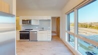Located in Charlotte's vibrant NoDa neighborhood, this modern single-floor unit at 1824 N Brevard St offers a thoughtfully designed layout with clean lines and contemporary finishes throughout. Light wood-tone flooring flows seamlessly across the living areas, complementing the neutral palette of crisp white walls and clean trim work.

The open living and dining area is defined by an impressive bank of oversized windows that frame sweeping views of the Charlotte skyline and surrounding cityscape, flooding the space with natural light throughout the day. The kitchen is well-appointed with light wood and white cabinetry, a soft gray subway tile backsplash, stainless steel appliances including a side-by-side refrigerator with ice maker, an electric range, dishwasher, and built-in microwave.

The bedrooms are generously proportioned, each featuring large windows that continue the theme of abundant natural light and exterior views. Natural wood-accented interior doors add warmth to the otherwise modern aesthetic.

Two bathrooms serve the unit: one features a full tub-shower combination with white tile surround, while the primary bathroom is equipped with a dual-sink vanity with a quartz countertop, a large wall mirror, and a separate tiled walk-in shower, offering a clean and functional design ideal for everyday living.