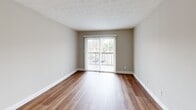 Located at 5700 Pleasant Ridge Rd in Knoxville, Tennessee, this one-bedroom, one-bathroom unit offers a well-organized, single-floor layout with wood-look flooring carried consistently throughout every room. The combined kitchen and living area forms the heart of the unit, with a sliding glass door flanked by vertical blinds opening to a private balcony that brings in natural light and outdoor views. The kitchen is outfitted with white cabinetry, granite-style countertops, a dishwasher, refrigerator, and an electric range, all set against a clean, neutral color palette. A textured ceiling adds a subtle design element to the living space. The bedroom is a comfortable size, featuring a window with outdoor views, two closets offering generous storage, and access to the hallway. The full bathroom includes a tub/shower combination with built-in corner shelving and chrome fixtures. Additional functional spaces include a dedicated utility room and a hallway connecting the rooms. Neutral gray walls, white trim, and warm wood-look floors create a cohesive, move-in-ready aesthetic throughout this practical and well-appointed Knoxville residence.