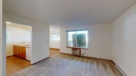 Located at 5317 Palouse Hwy in Spokane, WA, this well-organized one-bedroom, one-bathroom unit offers a practical and comfortable single-floor layout. The living area features soft carpeting and large windows that invite generous natural light while providing views of the surrounding greenery. A wall-mounted HVAC unit ensures climate control convenience.

The kitchen is designed with an open pass-through concept, featuring warm wood cabinetry, a full suite of white appliances including a refrigerator, electric range, and microwave, paired with a smooth countertop peninsula that separates the kitchen from the living space. Wood-style flooring adds warmth to the kitchen and connecting areas.

The bedroom is a comfortable, carpeted retreat with a window fitted with blinds for light control and privacy, complemented by a baseboard heater. A dedicated closet provides organized storage.

The bathroom includes a warm wood-toned vanity with ample cabinetry, a wide mirror with overhead lighting, and a tub/shower combination. Wood-style flooring completes the clean, functional aesthetic.

A standout feature of this unit is the in-unit laundry area, equipped with a full-sized washer and dryer alongside additional shelving, offering exceptional everyday convenience. Clean white walls and consistent trim throughout give the space a bright, move-in-ready feel.