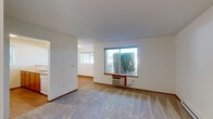 Located at 5317 Palouse Hwy in Spokane, WA, this well-organized one-bedroom, one-bathroom unit offers a practical and comfortable single-floor layout. The living area features soft carpeting and large windows that invite generous natural light while providing views of the surrounding greenery. A wall-mounted HVAC unit ensures climate control convenience.

The kitchen is designed with an open pass-through concept, featuring warm wood cabinetry, a full suite of white appliances including a refrigerator, electric range, and microwave, paired with a smooth countertop peninsula that separates the kitchen from the living space. Wood-style flooring adds warmth to the kitchen and connecting areas.

The bedroom is a comfortable, carpeted retreat with a window fitted with blinds for light control and privacy, complemented by a baseboard heater. A dedicated closet provides organized storage.

The bathroom includes a warm wood-toned vanity with ample cabinetry, a wide mirror with overhead lighting, and a tub/shower combination. Wood-style flooring completes the clean, functional aesthetic.

A standout feature of this unit is the in-unit laundry area, equipped with a full-sized washer and dryer alongside additional shelving, offering exceptional everyday convenience. Clean white walls and consistent trim throughout give the space a bright, move-in-ready feel.