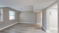 This 2-bedroom, 1-bathroom single-floor residence offers a clean, modern aesthetic throughout, characterized by neutral warm-gray walls, light wood-look flooring, and crisp white trim that create a cohesive and inviting atmosphere. Natural light filters in through multiple windows fitted with blinds across all rooms, enhancing the bright and airy feel of the space.

The kitchen is a standout feature, showcasing white shaker-style cabinetry with matte black hardware, speckled granite countertops, a subway tile backsplash, and a black gooseneck faucet at the undermount sink. A gas range, built-in range hood, and stainless steel refrigerator complete the functional and stylish cooking space.

The primary bedroom offers a comfortable footprint with built-in open shelving and access to additional storage, while multiple windows provide ample natural light. The second bedroom is similarly well-lit and features clean lines with easy access to hallways connecting the unit's living areas.

The living room is a generous, open space with light hardwood flooring and multiple windows that invite natural light. The bathroom is finished with full white square tile surrounding a soaking bathtub, accented by a window for ventilation. Together, these rooms compose a well-organized, move-in-ready residence with thoughtful, updated finishes throughout.
