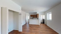 Located on the upper level at 671 Woodward #16 in San Marcos, this thoughtfully designed unit offers a clean, modern aesthetic with a bright and open feel throughout. The main living area features rich hardwood-style flooring and a seamless flow into the kitchen, which is equipped with warm wood cabinetry, stainless steel appliances including a gas range, over-the-range microwave, and refrigerator, as well as a peninsula with a built-in sink — ideal for both cooking and casual dining. Recessed lighting illuminates the open-concept space, and access to a private balcony provides sweeping views of the surrounding hills and open landscape under the expansive San Marcos sky. The bedrooms offer plush carpeting and generous closet space with sliding doors, while natural light enters through multiple windows. The bathroom includes a glass-enclosed shower-tub combination with a sleek chrome frame. White walls and neutral finishes throughout create a clean, versatile interior ready to accommodate a variety of styles. The unit is accessed via an interior staircase and offers a well-organized layout that maximizes comfort and functionality.