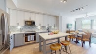 Located at 5400 Broken Sound Blvd NW in Boca Raton, Florida, this single-floor residence offers a thoughtfully designed open-concept layout that seamlessly connects the kitchen, dining, and living areas. The kitchen is outfitted with white upper cabinetry, gray lower cabinetry, stainless steel appliances, a mosaic tile backsplash, and a central island with bar seating — ideal for both cooking and casual dining. Light hardwood flooring flows throughout the main living areas, enhancing the bright, airy atmosphere created by large windows with views of lush Florida greenery.

The living room is generously proportioned, featuring a ceiling fan, ample natural light, and a relaxed coastal aesthetic with neutral tones and blue accents. The bedrooms are well-appointed, each offering carpeted flooring, large windows, and calming color palettes — one featuring a serene light blue accent wall and another showcasing a bold deep-blue feature wall with framed botanical artwork.

The primary bathroom is spa-like, featuring a dual-sink vanity with gray cabinetry, white quartz countertops, large-format tile flooring, a soaking tub, and a separate glass-enclosed walk-in shower with matte black fixtures. A dedicated in-unit laundry closet with a stacked washer and dryer adds everyday convenience.