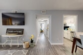 Located at 107 Yester Oaks Way E in Greensboro, NC, this single-floor, 2-bedroom, 1-bathroom home offers a thoughtfully designed layout with a cohesive, neutral color palette throughout. Light gray walls and wood-look plank flooring extend across the main living areas, lending a clean, modern aesthetic that ties the spaces together seamlessly.

The living room is a welcoming focal point, featuring a sliding glass door that opens to a private balcony with outdoor views of surrounding greenery, allowing natural light to fill the space. A central hallway connects the living area to the rest of the home, providing clear and functional circulation between rooms.

The kitchen features white cabinetry, light speckled countertops, a double stainless steel sink, and stainless steel appliances, including a dishwasher and microwave. Adjacent to the kitchen, the dining room offers dedicated space for meals and entertaining, also finished with wood-look flooring.

The primary bedroom is generously sized with plush carpeting, and the second bedroom offers similar comfort. The bathroom includes white cabinetry, a light countertop, a large mirror, and classic hexagonal tile flooring. A dedicated laundry area and two closets add practical storage throughout the home.