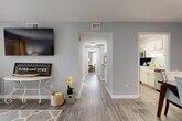 Located at 107 Yester Oaks Way E in Greensboro, NC, this single-floor, 2-bedroom, 1-bathroom home offers a thoughtfully designed layout with a cohesive, neutral color palette throughout. Light gray walls and wood-look plank flooring extend across the main living areas, lending a clean, modern aesthetic that ties the spaces together seamlessly.

The living room is a welcoming focal point, featuring a sliding glass door that opens to a private balcony with outdoor views of surrounding greenery, allowing natural light to fill the space. A central hallway connects the living area to the rest of the home, providing clear and functional circulation between rooms.

The kitchen features white cabinetry, light speckled countertops, a double stainless steel sink, and stainless steel appliances, including a dishwasher and microwave. Adjacent to the kitchen, the dining room offers dedicated space for meals and entertaining, also finished with wood-look flooring.

The primary bedroom is generously sized with plush carpeting, and the second bedroom offers similar comfort. The bathroom includes white cabinetry, a light countertop, a large mirror, and classic hexagonal tile flooring. A dedicated laundry area and two closets add practical storage throughout the home.