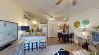 This single-story, 2-bedroom, 1-bathroom home offers a thoughtfully arranged floor plan that maximizes its compact footprint. The open-concept living, dining, and kitchen area forms the heart of the home, creating a seamless and social atmosphere. The kitchen is well-appointed with white cabinetry, a full suite of appliances including a refrigerator, range, microwave, and dishwasher, and a breakfast bar with barstool seating — ideal for casual dining. A dedicated dining area adjacent to the kitchen provides additional space for meals and entertaining. The living room features plush carpeting, a ceiling fan, and a bright window that brings in natural light. Both bedrooms are comfortably sized, carpeted, and equipped with ceiling fans, offering a restful retreat. The primary bedroom is generously proportioned with room for full bedroom furniture. The shared bathroom includes a vanity with ample storage, a framed mirror, and a shower-tub combination. A dedicated in-unit laundry area accommodates a full-size washer and dryer with built-in shelving above for storage. Hardwood-style flooring runs through the kitchen and dining areas, complementing the warm, neutral tones found throughout the home.