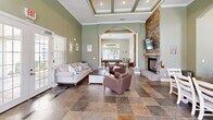 Located at Belmere Luxury Court in Houma, Louisiana, this elegantly designed single-floor space offers a seamless blend of comfort and functionality across its thoughtfully arranged rooms.

The centerpiece of the space is a spacious living room distinguished by soaring ceilings with decorative coffered detailing, warm sage-green walls, and rich slate tile flooring. A dramatic floor-to-ceiling stacked stone fireplace anchors the room, complemented by arched doorways framed with classic white columns that lead into the adjoining dining area. French doors flood the space with natural light and provide views of the outdoor pool area.

The dining room connects fluidly to the living space through the arched colonnade, offering additional seating and casual bar-height counter space along windowed walls that invite abundant natural light.

The kitchen is well-equipped with granite countertops, crisp white cabinetry, stainless steel appliances including a side-by-side refrigerator, double sink, and ample storage — all brightened by large windows overlooking the grounds.

A dedicated office features an extended granite-topped work surface accommodating multiple workstations, light tile flooring, and a glass-paneled door providing direct exterior access and natural light. Together, these spaces create a polished, welcoming environment suited for both productivity and leisure.