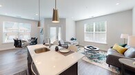This single-floor residence is designed with a clean, contemporary aesthetic that emphasizes open-concept living. The kitchen serves as a central hub of the layout, featuring dark espresso cabinetry, stainless steel appliances, a white quartz countertop island with an undermount sink, and stylish pendant lighting overhead. Wood-look flooring extends throughout the main living areas, lending warmth and visual continuity. The kitchen flows directly into a bright living room that benefits from generous natural light through large windows and access to the outdoors via glass-paned French doors.

The primary bedroom offers plush carpeting, a ceiling fan, and a sliding barn-style door that opens to a well-organized walk-in closet. Its en-suite bathroom is appointed with a dark wood double-vanity, white quartz countertops, a large mirror with bright vanity lighting, and a glass-enclosed walk-in shower with herringbone-patterned tile. A second bedroom features soft carpet, a ceiling fan, natural light from a sizeable window, and a dedicated walk-in closet with built-in shelving. The second bathroom includes a glass-enclosed tub and shower combination with white tile surround and wood-look flooring, maintaining the residence's cohesive modern style throughout.
