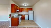 Located at 401 E Gibbsboro Rd in Lindenwold, NJ, this single-floor unit offers a practical and well-maintained layout with consistent wood-look flooring throughout the main living areas. The spacious living room provides an open feel, with neutral-toned walls, baseboard heating, and natural light filtering through windows fitted with blinds. A dedicated bedroom features soft carpeting underfoot, a generous closet with bifold doors, and a window that looks out to the surrounding exterior. An additional room with a window and baseboard heating offers flexibility as a second bedroom, office, or den. The kitchen is equipped with rich wood-toned cabinetry, granite-style countertops, a gas range, dishwasher, and refrigerator — all finished in white — alongside wood-look flooring that ties the space together. The bathroom includes a warm wood-toned vanity with ample cabinet storage, a white countertop, a lighted mirror, a window for natural ventilation, and wood-look tile flooring. Baseboard heating is present throughout the unit, ensuring consistent comfort. The overall design is clean and functional, with a neutral color palette that creates a bright, welcoming atmosphere throughout.