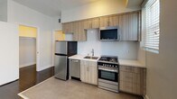 Located at 6500 Yucca St in the heart of Hollywood, Los Angeles, this single-floor unit offers a clean, modern aesthetic throughout. Dark hardwood flooring runs consistently across the main living areas and bedrooms, providing a rich contrast to the crisp white walls and trim that define the interior palette.

The kitchen is well-appointed with contemporary light wood cabinetry extending to the ceiling for ample storage, white quartz countertops, and a full suite of stainless steel appliances including a refrigerator, gas range with oven, dishwasher, and over-the-range microwave. Natural light enters through slatted window blinds, brightening the functional layout.

The living area is generously proportioned, featuring a ceiling fan with integrated lighting and open sightlines connecting to adjacent rooms. Multiple windows fitted with horizontal blinds allow for natural light while maintaining privacy. The bedrooms are well-sized, each with large windows — some equipped with window AC units — and the same polished dark hardwood flooring.

Two bathrooms are present, each featuring a tub-shower combination with clean white tile or surround, updated chrome fixtures, and light wood vanity cabinetry with undermount sinks. Natural light filters in through frosted-blind windows. The overall ambiance is fresh, contemporary, and move-in ready.