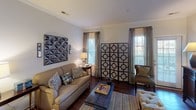 This single-floor residence offers a thoughtfully designed layout that balances functionality with style. The open-concept kitchen is equipped with stainless steel appliances, including a refrigerator, range, and microwave, complemented by white cabinetry, granite countertops, and a peninsula that provides additional workspace and seating. Rich hardwood flooring flows throughout the main living areas, adding warmth and continuity to the space.

The living room is generously proportioned, featuring crown molding, large windows that allow ample natural light, and ceiling fans that enhance comfort. A dedicated dining area accommodates a full-sized table beneath an elegant pendant light, with crown molding and wainscoting details adding a refined touch.

The bedrooms are carpeted for comfort, each featuring ceiling fans and large windows. One bedroom includes a walk-in closet with built-in shelving, offering excellent storage. A second bedroom provides access to a small study or den area. The bathroom is clean and functional, featuring a full soaking tub and shower combination.

Throughout the residence, neutral wall tones create a calm, versatile backdrop, while architectural details such as crown molding and panel doors lend a classic character to the overall aesthetic.