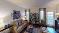 This single-floor residence offers a thoughtfully designed layout that balances functionality with style. The open-concept kitchen is equipped with stainless steel appliances, including a refrigerator, range, and microwave, complemented by white cabinetry, granite countertops, and a peninsula that provides additional workspace and seating. Rich hardwood flooring flows throughout the main living areas, adding warmth and continuity to the space.

The living room is generously proportioned, featuring crown molding, large windows that allow ample natural light, and ceiling fans that enhance comfort. A dedicated dining area accommodates a full-sized table beneath an elegant pendant light, with crown molding and wainscoting details adding a refined touch.

The bedrooms are carpeted for comfort, each featuring ceiling fans and large windows. One bedroom includes a walk-in closet with built-in shelving, offering excellent storage. A second bedroom provides access to a small study or den area. The bathroom is clean and functional, featuring a full soaking tub and shower combination.

Throughout the residence, neutral wall tones create a calm, versatile backdrop, while architectural details such as crown molding and panel doors lend a classic character to the overall aesthetic.